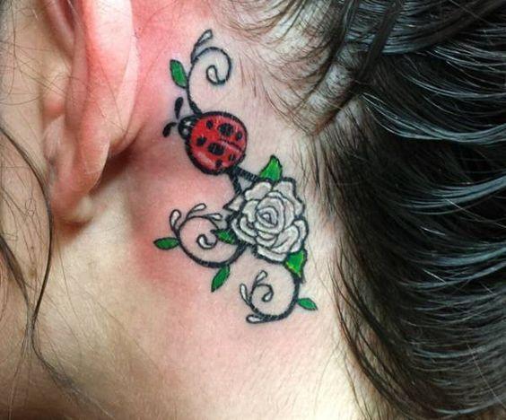 Marienkäfer Tattoo mit Blumen hinter dem Ohr