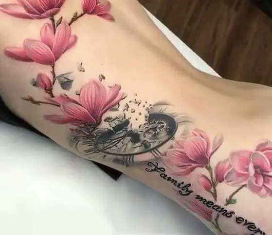 Suuri tatuointi magnoliasta ja kello naisen kehossa