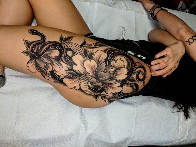 Tatuiruotės gėlės ir gyvatė ant kojos
