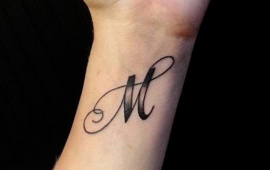 M raidės tatuiruotė ant riešo