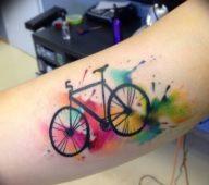 Тату велосипед на руке с разноцветными кляксами