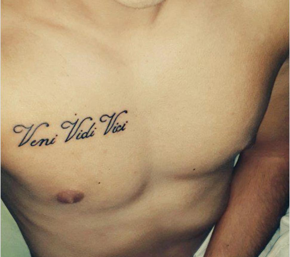 Photo of tattoo "Came, saw, conquered" in Latin on the body.